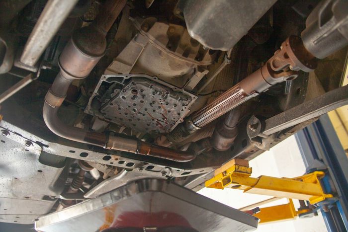 Undercarriage of a vehicle on a lift, showing exhaust pipes and a yellow jack stand | Bay's Auto Repair & Collision Services