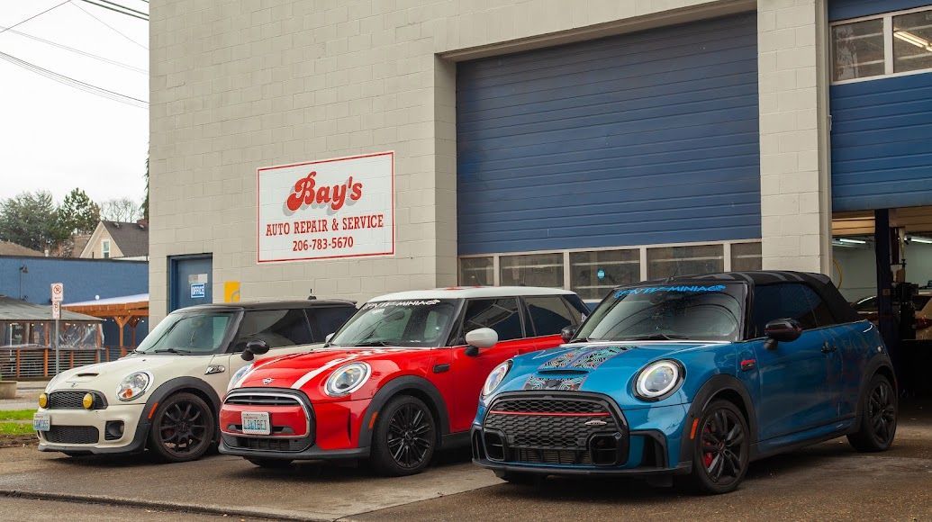 Three Mini Coopers parked outside a garage with a sign above the entrance | Bay's Auto Repair & Collision Services