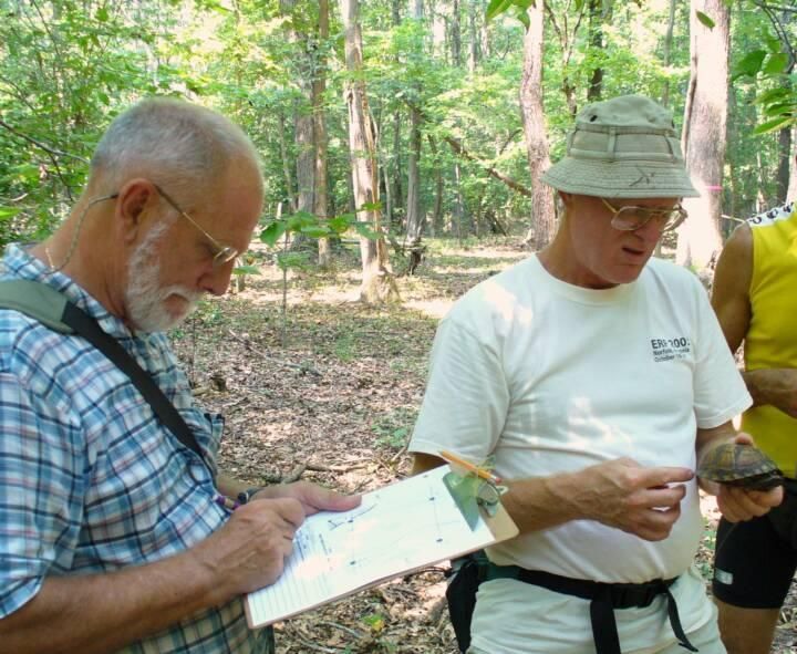 People studying a map in a wooded park during a nature walk