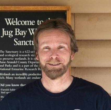 Smiling man standing in front of a sanctuary sign outdoors
