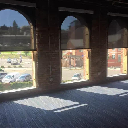 Sunlit room with arched windows overlooking parked cars and buildings outside