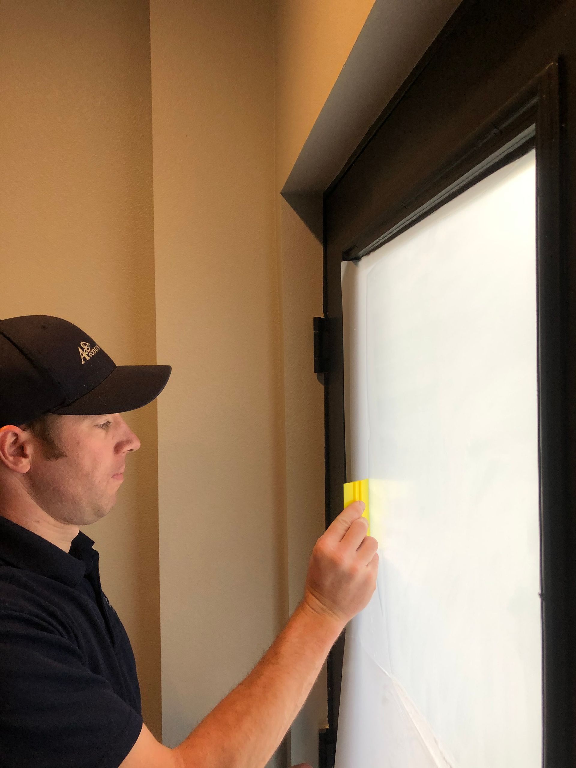 Man using a yellow tool to inspect a window frame indoors