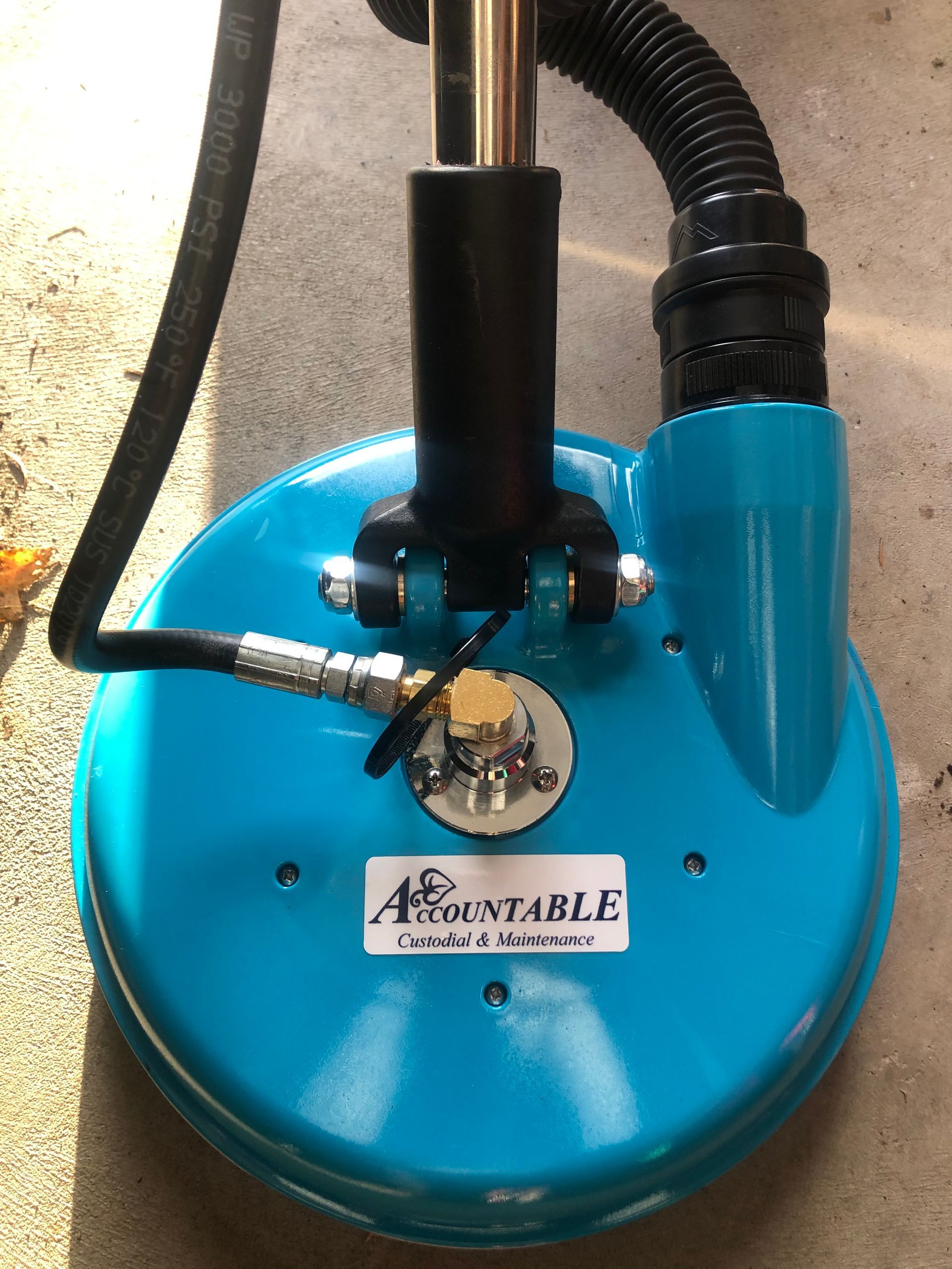 Blue metal floor machine with hoses and a central pole, viewed from above