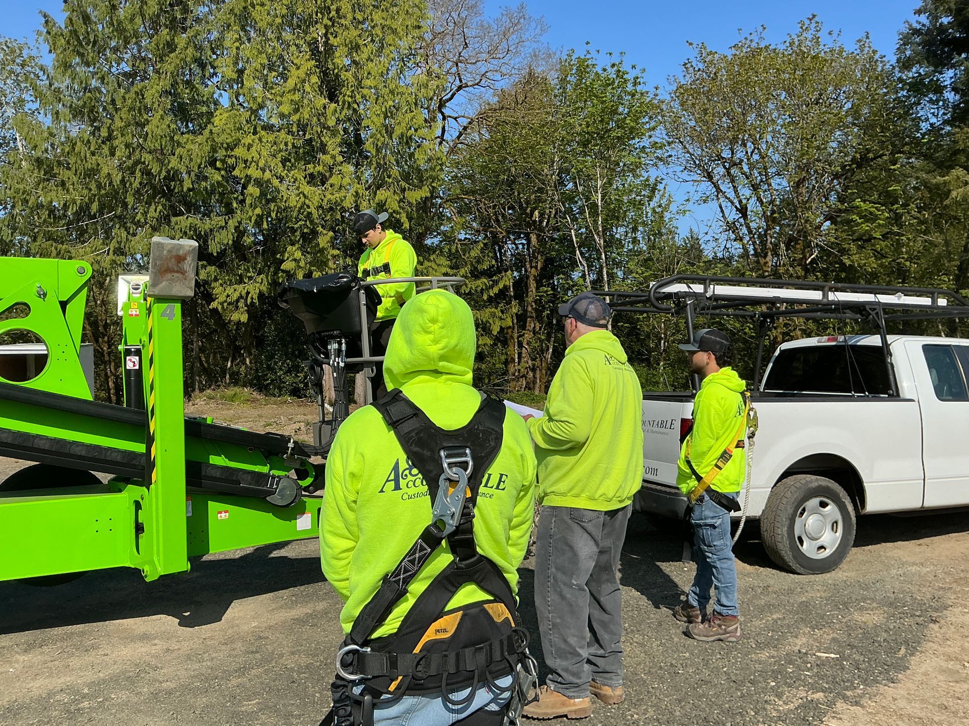Workers in neon safety gear loading equipment near a green trailer beside a white truck outdoors