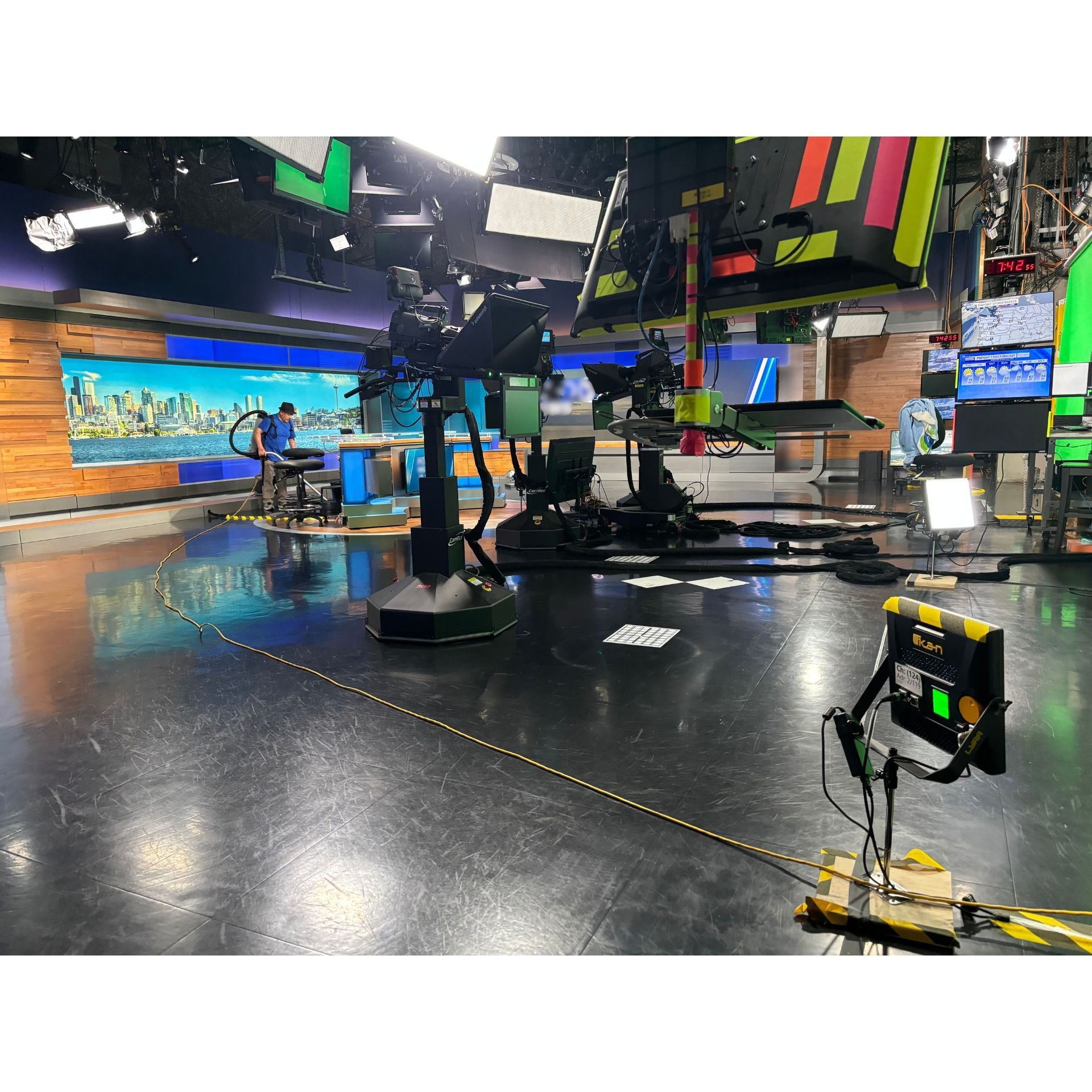 TV studio set with cameras, lights, and a glossy floor, seen from a wide angle