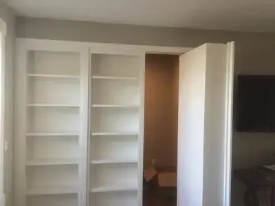 A room with a lot of shelves and a door that is open.