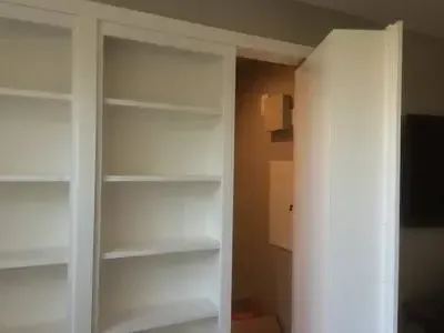 A room with white shelves and a door that is open.