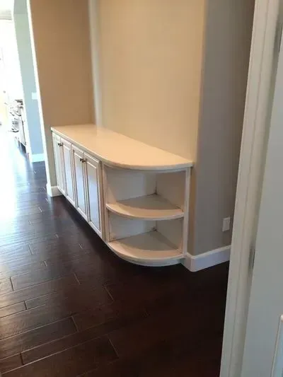 A white cabinet with a curved shelf in a hallway.