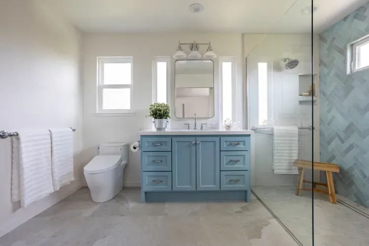 A bathroom with a toilet , sink , mirror and walk in shower.