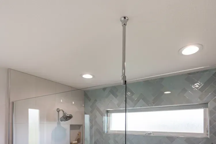 A bathroom with a walk in shower and a window.