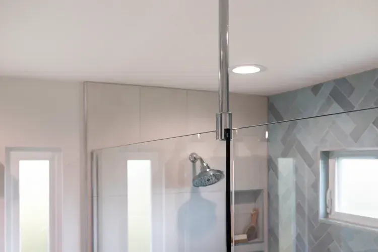 A bathroom with a walk in shower and a window.