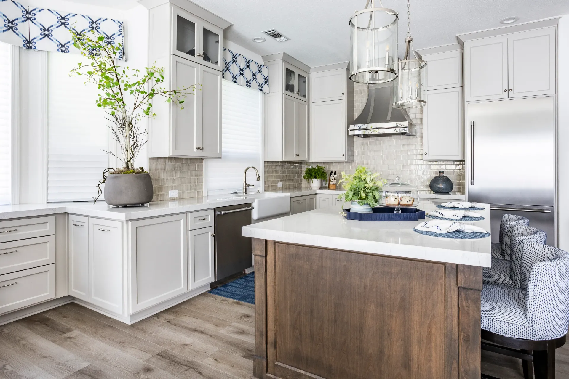 A kitchen with white cabinets , stainless steel appliances , and a large island.