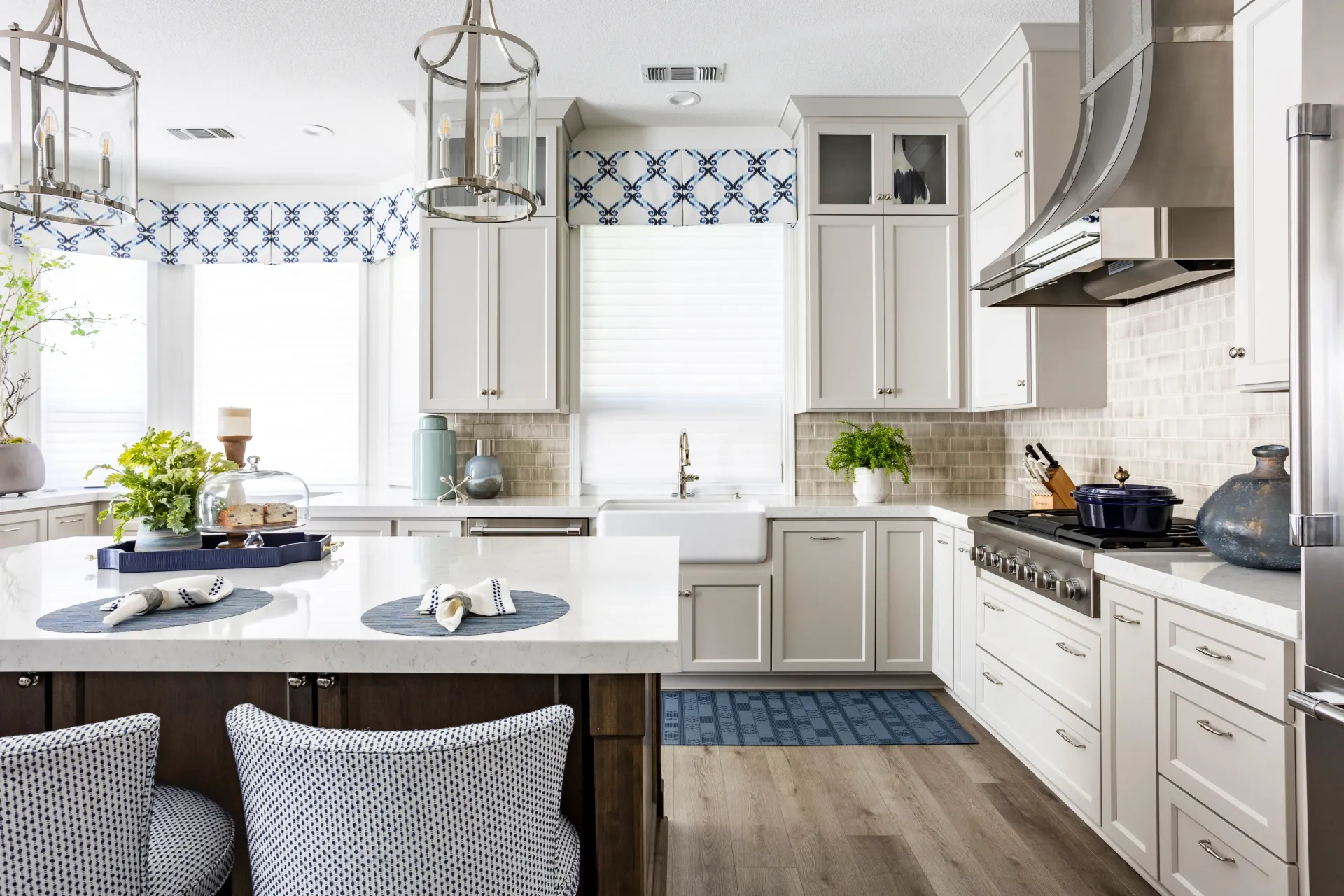 A kitchen with white cabinets , stainless steel appliances , and a large island.