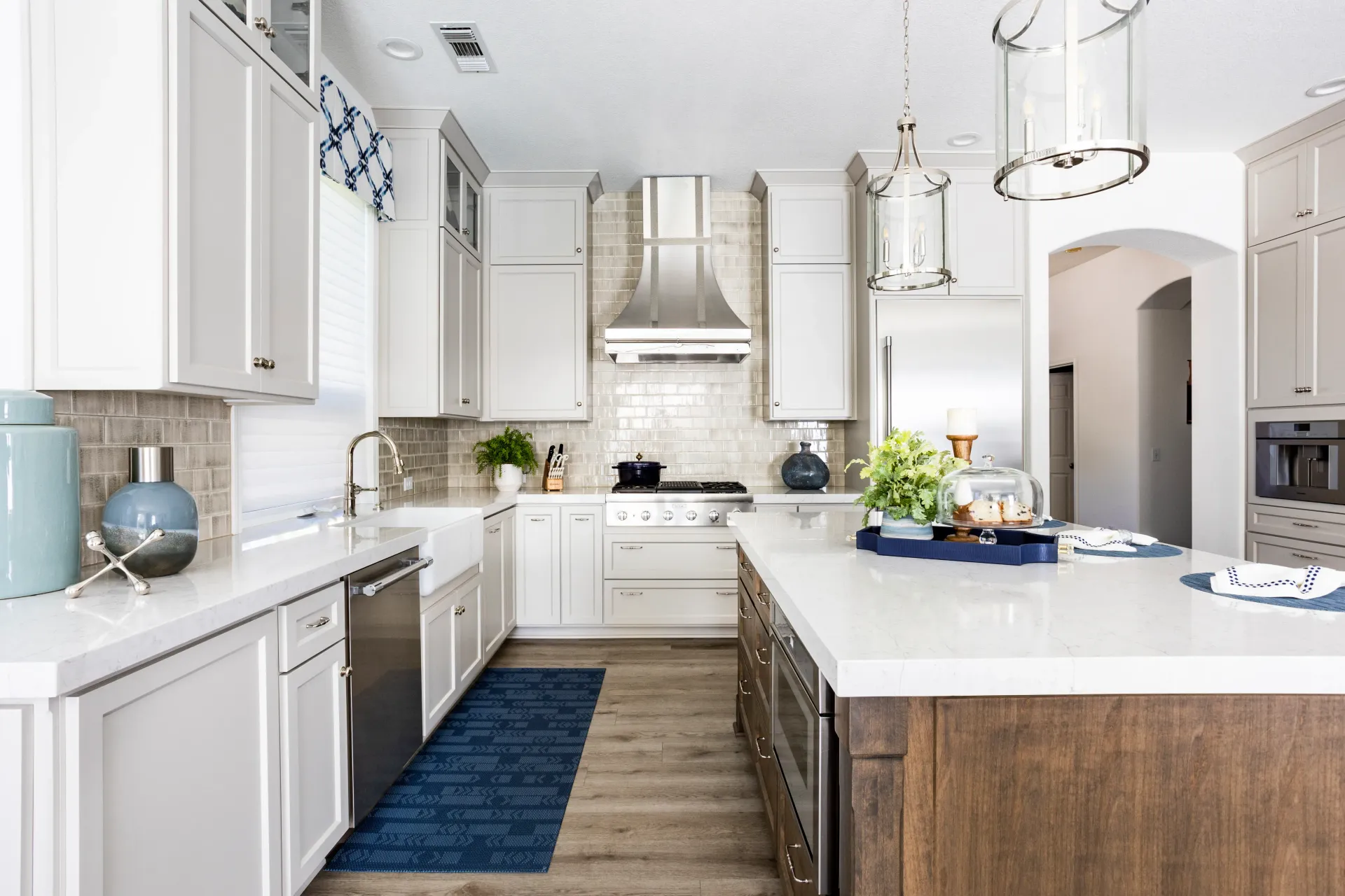 A kitchen with white cabinets , stainless steel appliances , and a large island.
