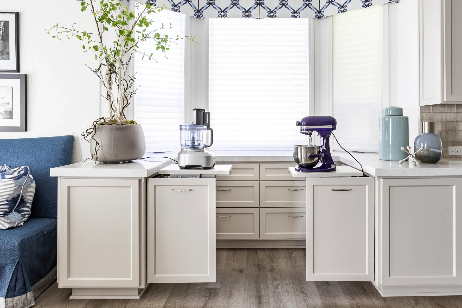 A kitchen with white cabinets , a blender , a dishwasher and a window.