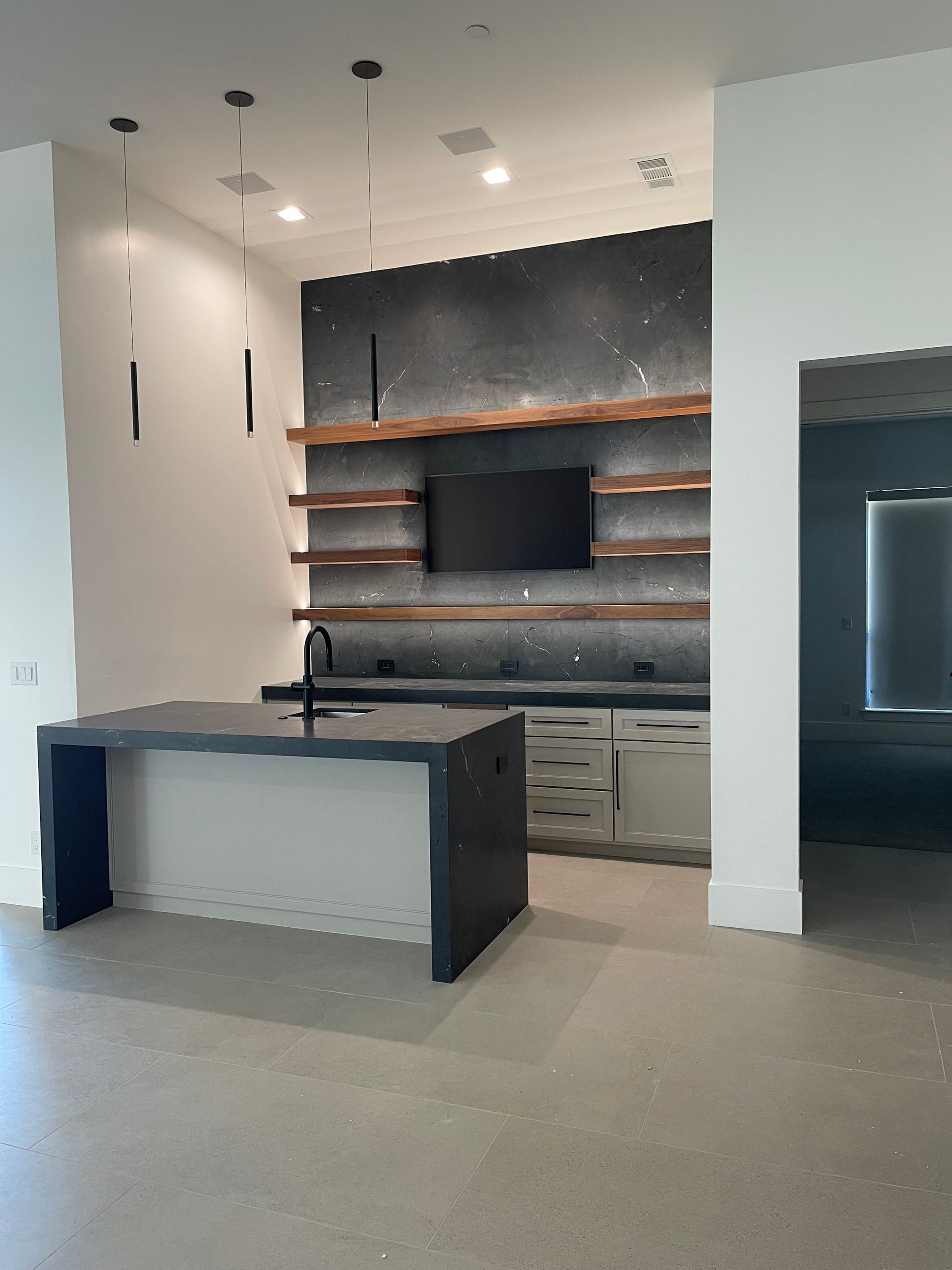 A kitchen with a large island and a flat screen tv on the wall