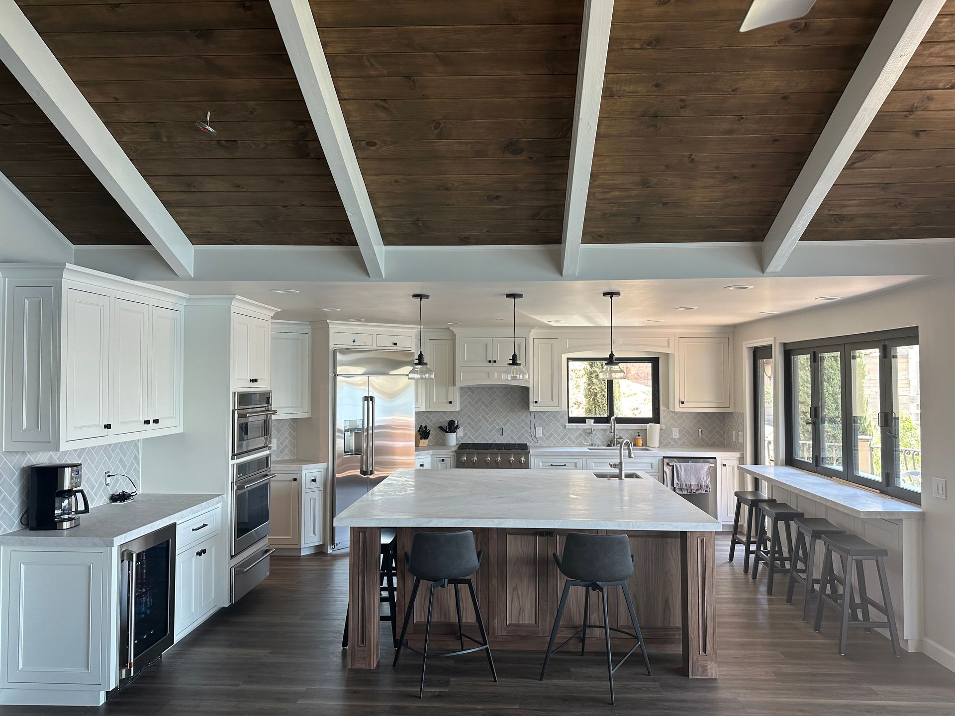 A kitchen with a large island in the middle and a wooden ceiling.