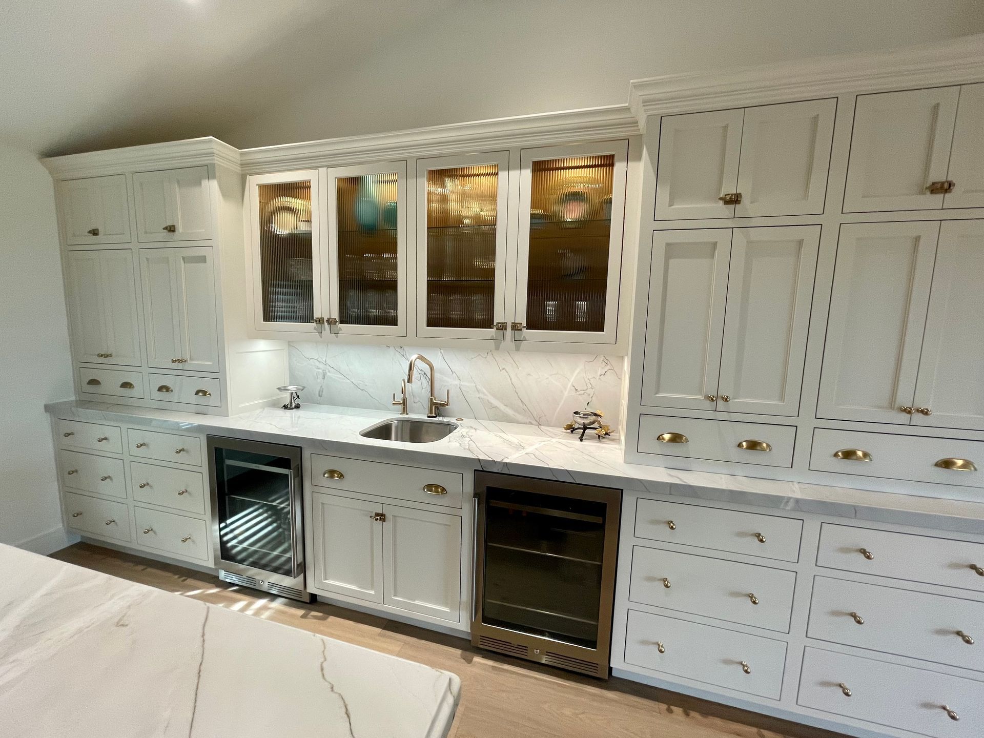 A kitchen with white cabinets , a sink , and a refrigerator.