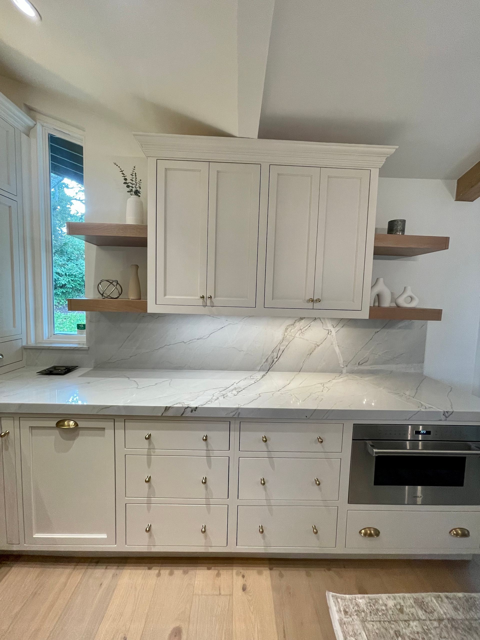 A kitchen with white cabinets and marble counter tops.