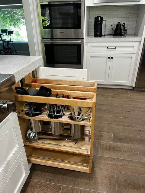 A kitchen with a pull out shelf filled with pots and pans.