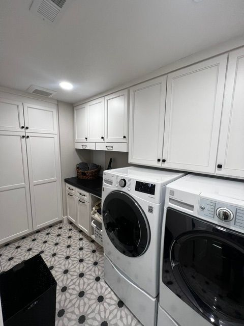 A laundry room with a washer and dryer and white cabinets.