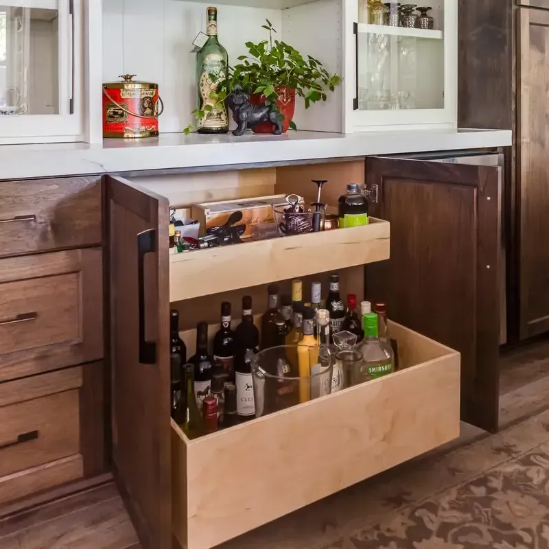 A wooden drawer filled with bottles of liquor in a kitchen