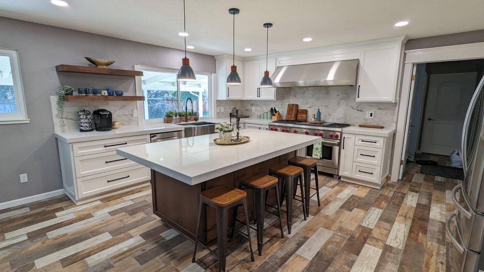 A kitchen with a large island and stools in it.