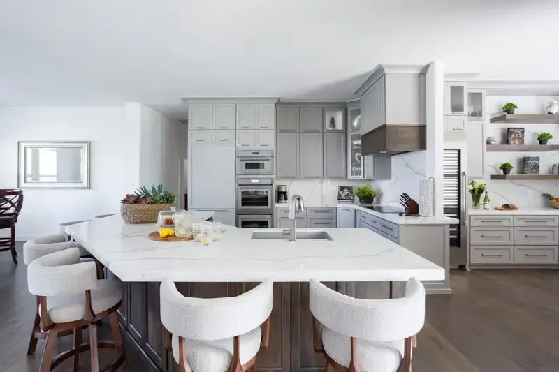 A kitchen with white cabinets , stainless steel appliances and a large island.