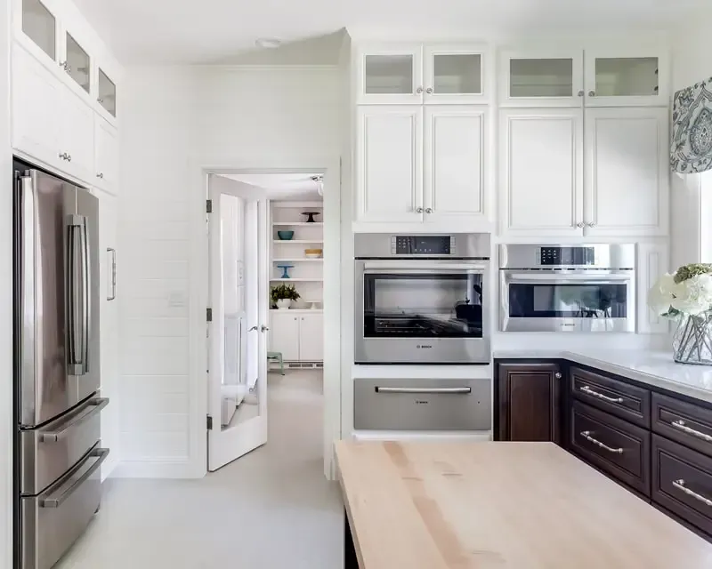 A kitchen with white cabinets , stainless steel appliances , a refrigerator and a microwave.