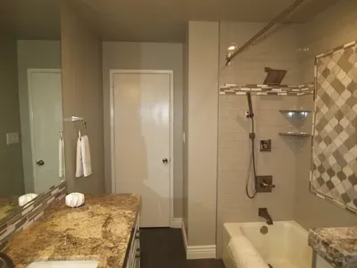 A bathroom with a tub , sink , mirror and shower.