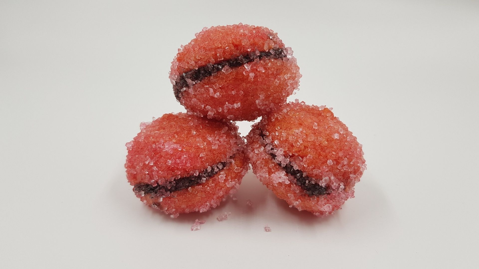 Tre palline rosse sono impilate una sopra l'altra su una superficie bianca.