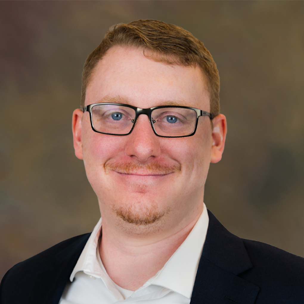 A man wearing glasses and a suit is smiling for the camera.