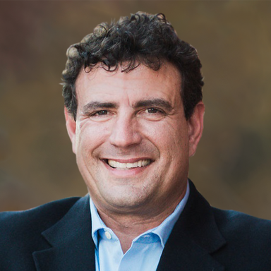 A man in a suit and blue shirt is smiling for the camera.