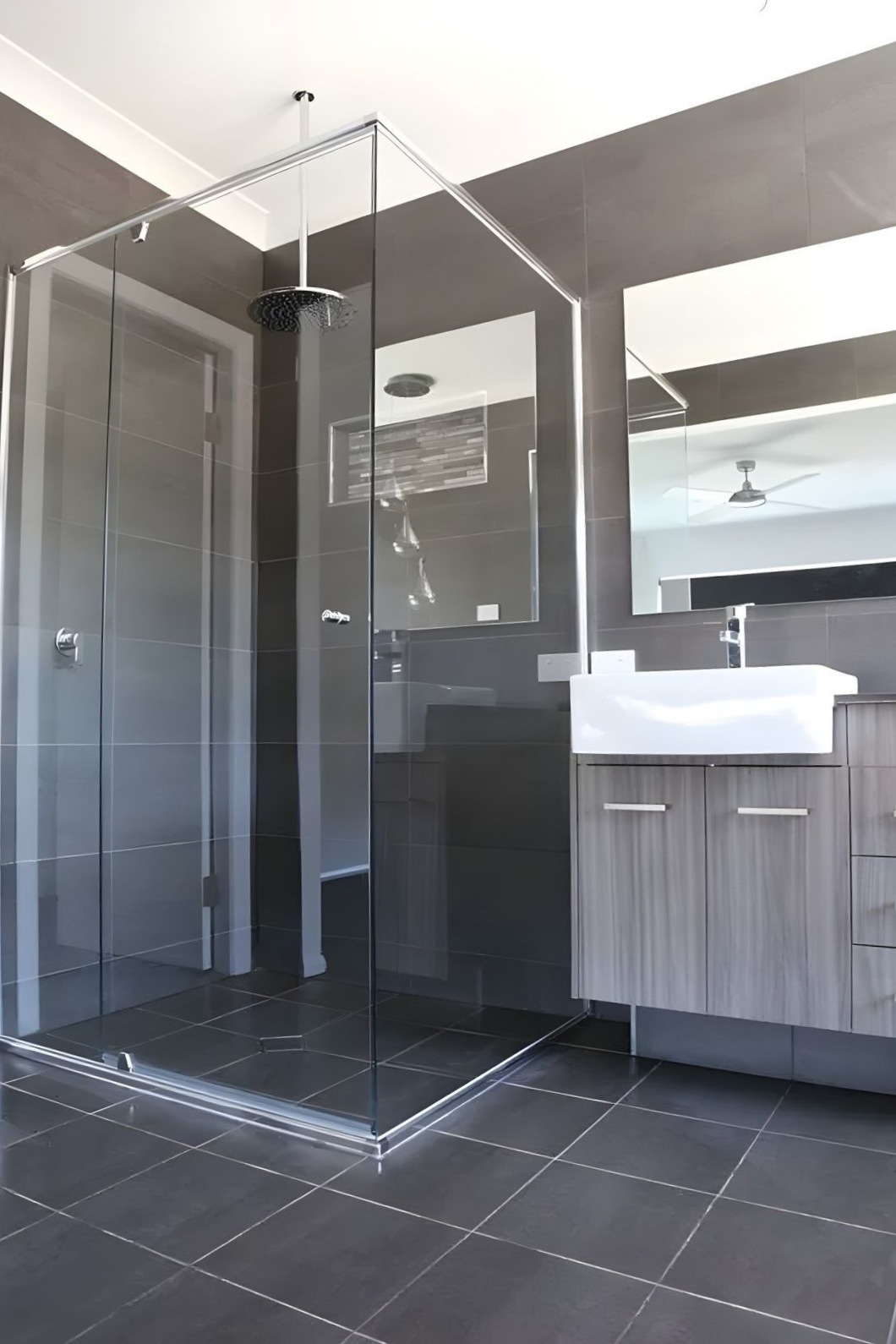 Modern Bathroom With a Glass Shower, Dark Gray Tiles, and a Vanity With a White Sink — North Coast Tiles in Grafton, NSW