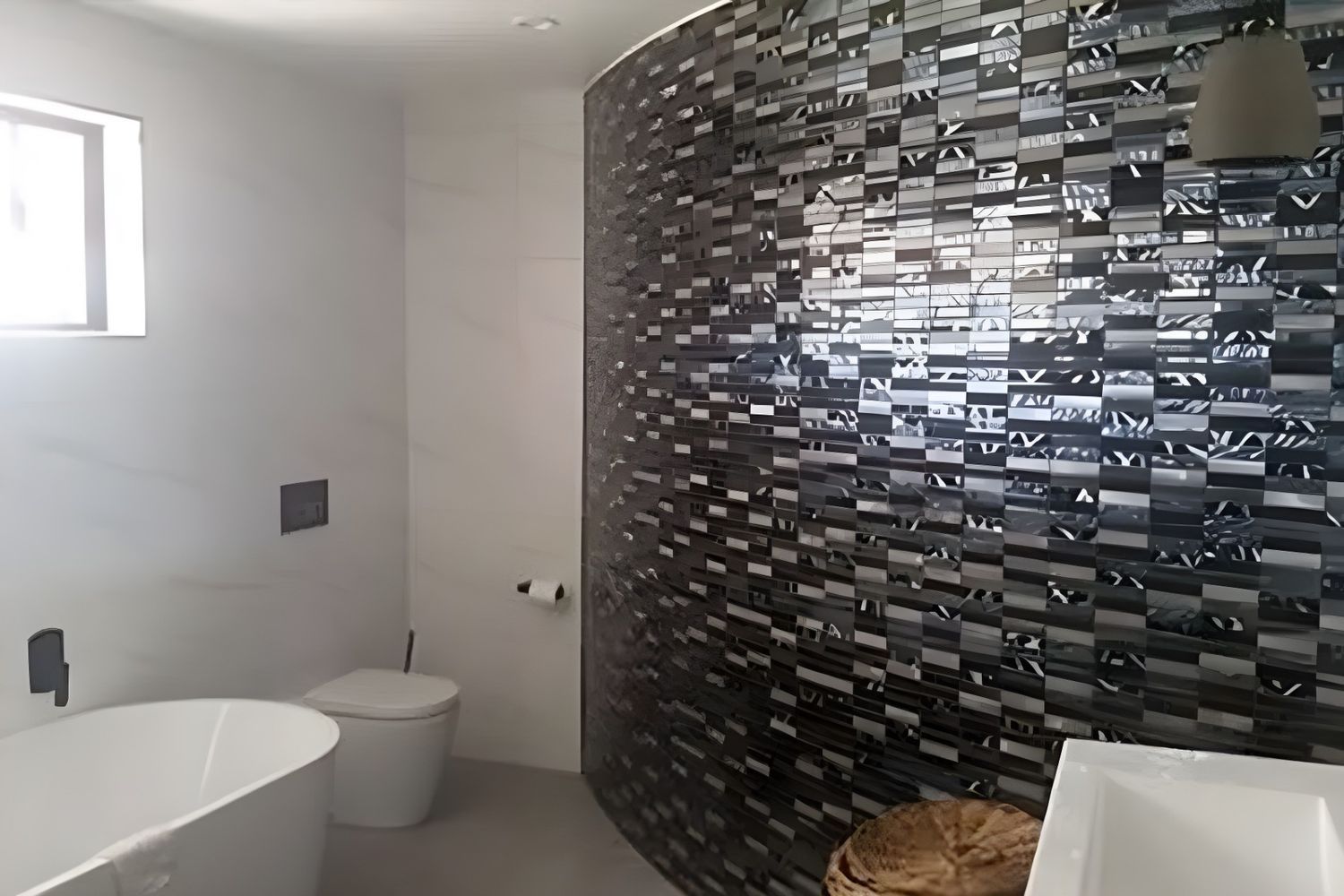 A Modern Bathroom With a Curved Accent Wall of Mosaic Tiles, a White Tub, Toilet, and Sink — North Coast Tiles in Grafton, NSW