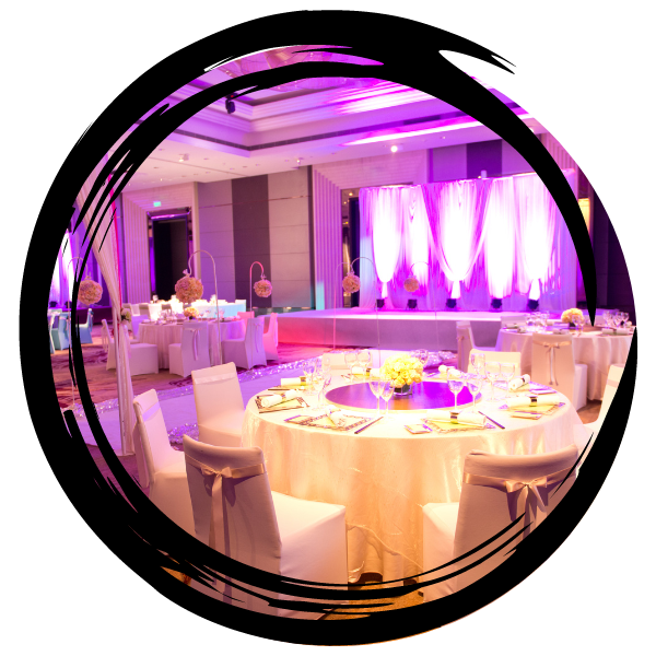Elegant banquet hall with round tables, white linens, and purple uplighting