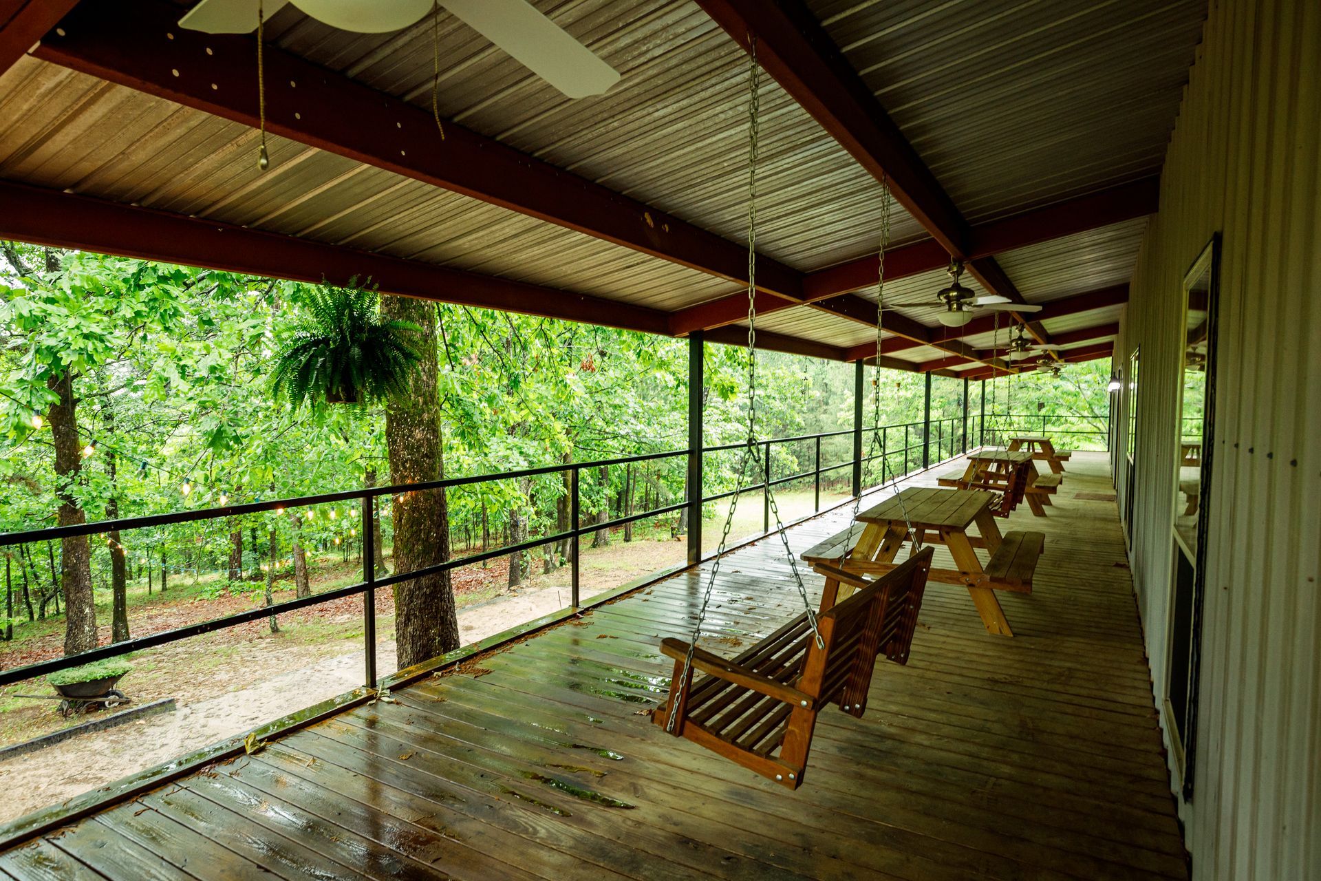 Covered wooden porch with rocking chairs overlooking lush green forest