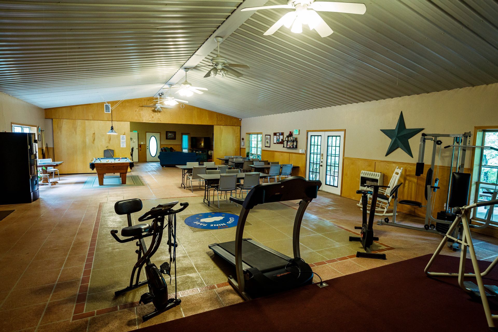 Spacious indoor gym with exercise bikes, treadmills, and weights on a polished floor.