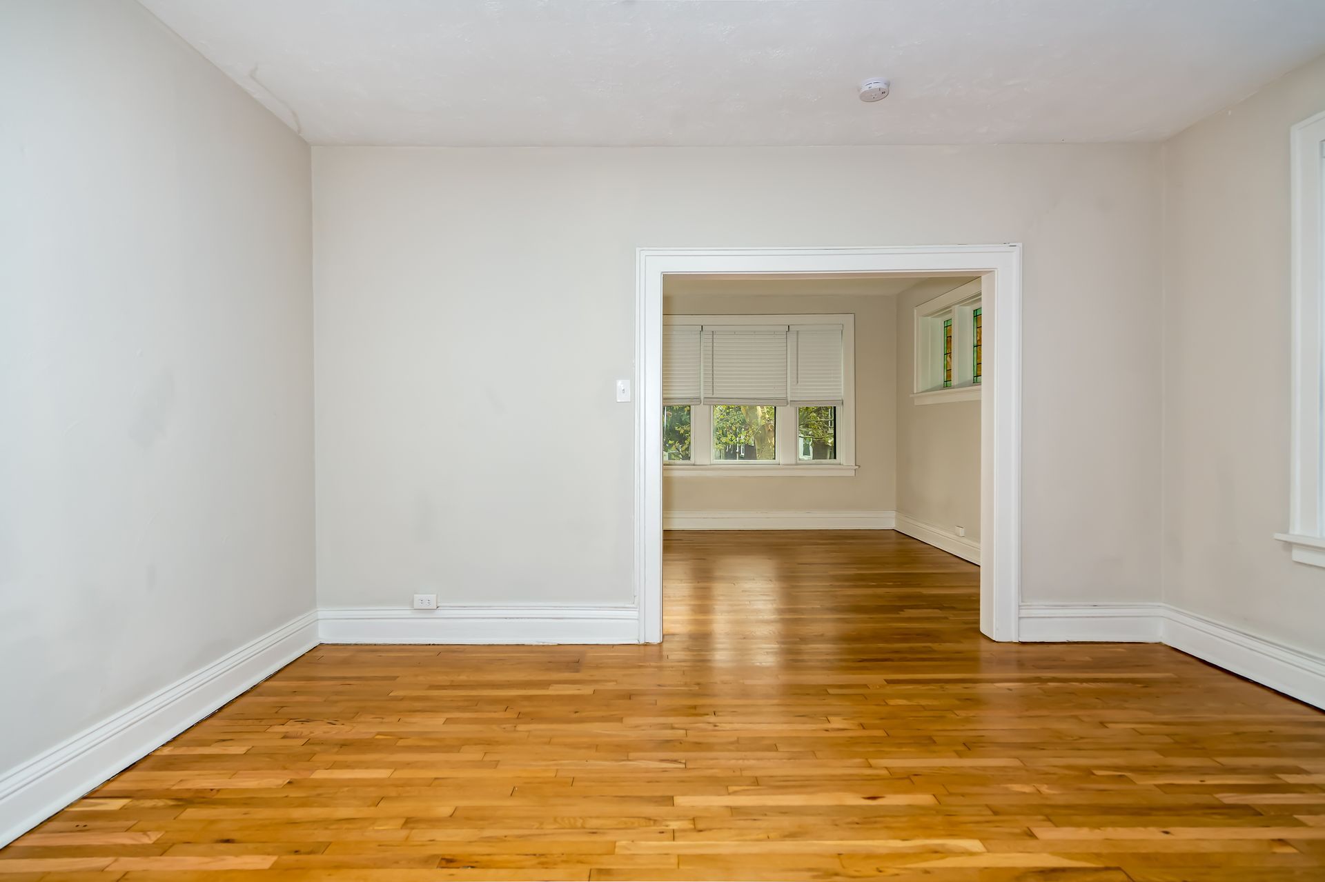 An empty room with hardwood floors and white walls