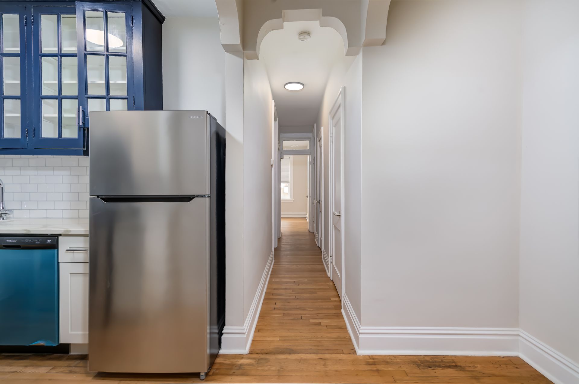 A stainless steel refrigerator is sitting in a kitchen next to a hallway.