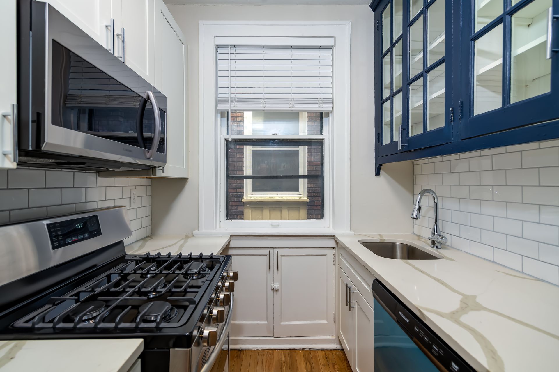 A kitchen with a stove , sink , and microwave.