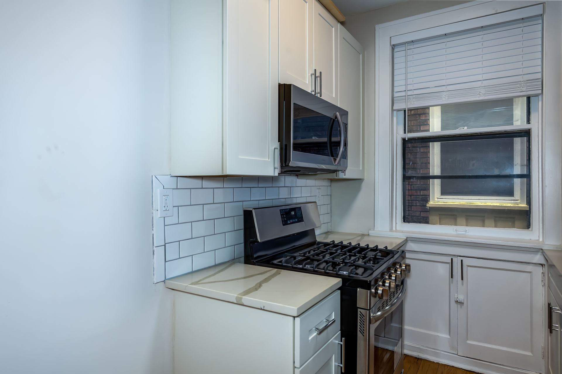 A kitchen with white cabinets and a stove and microwave