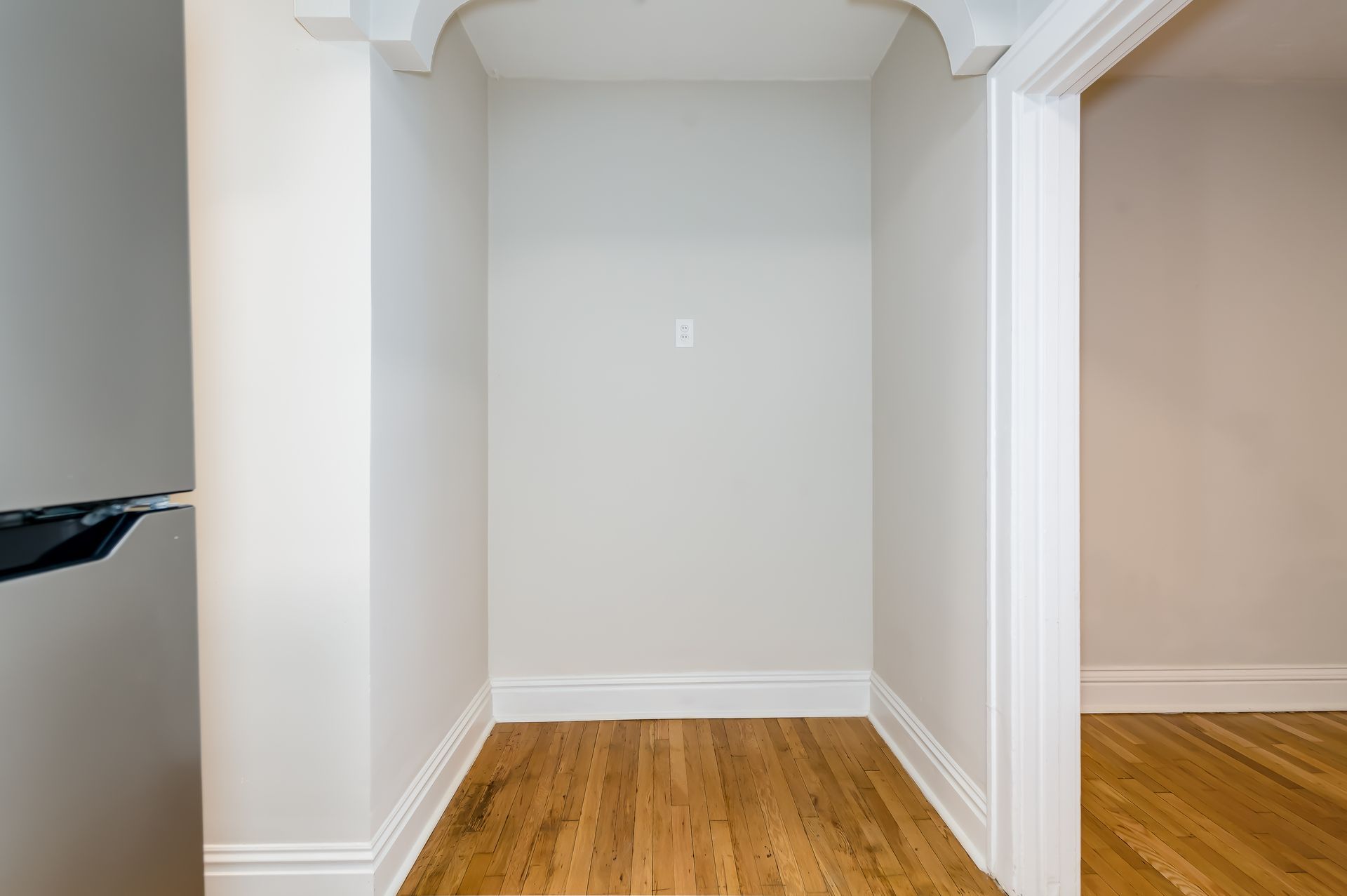 An empty room with hardwood floors and white walls.