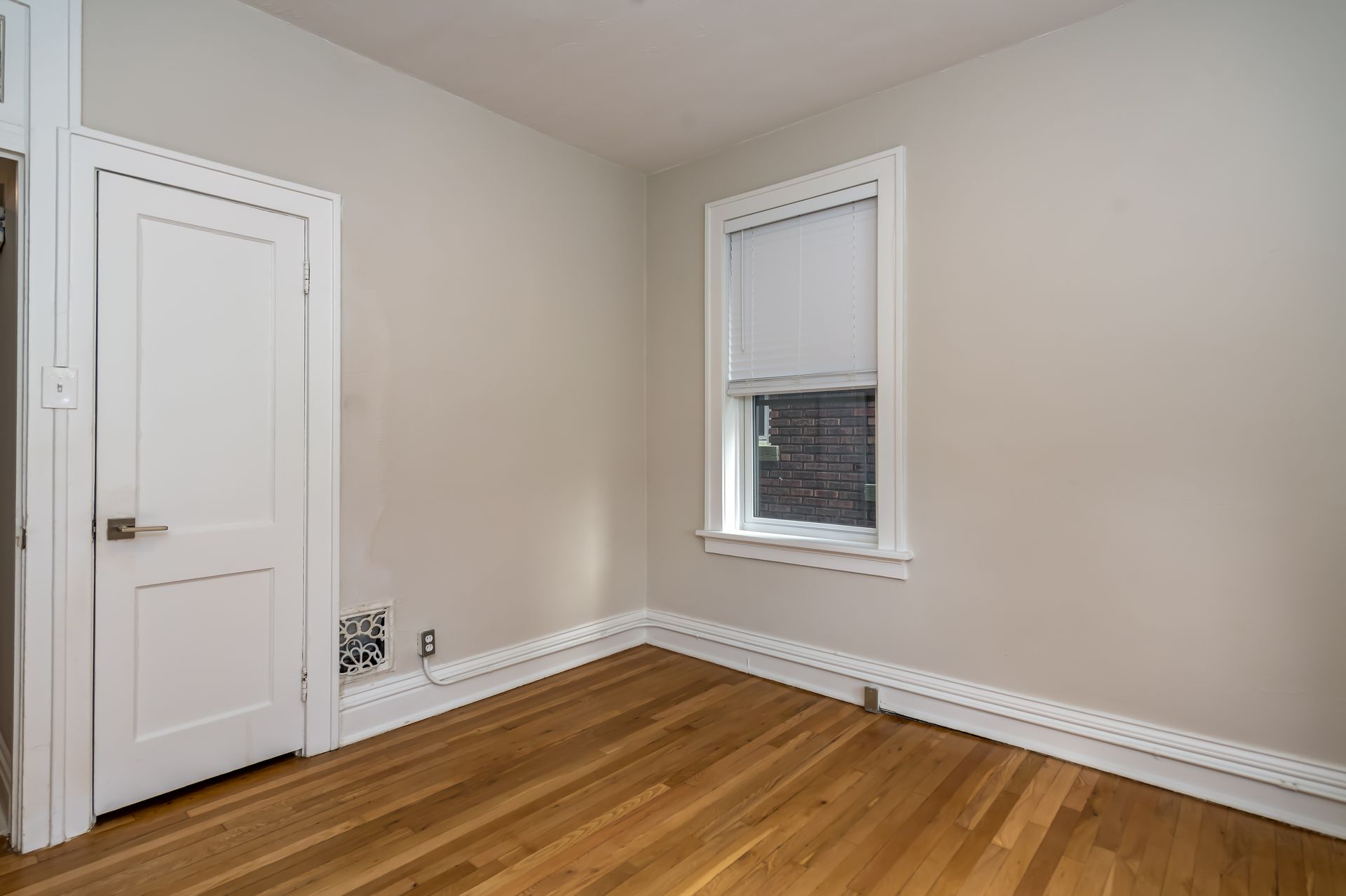 An empty room with hardwood floors and a window.