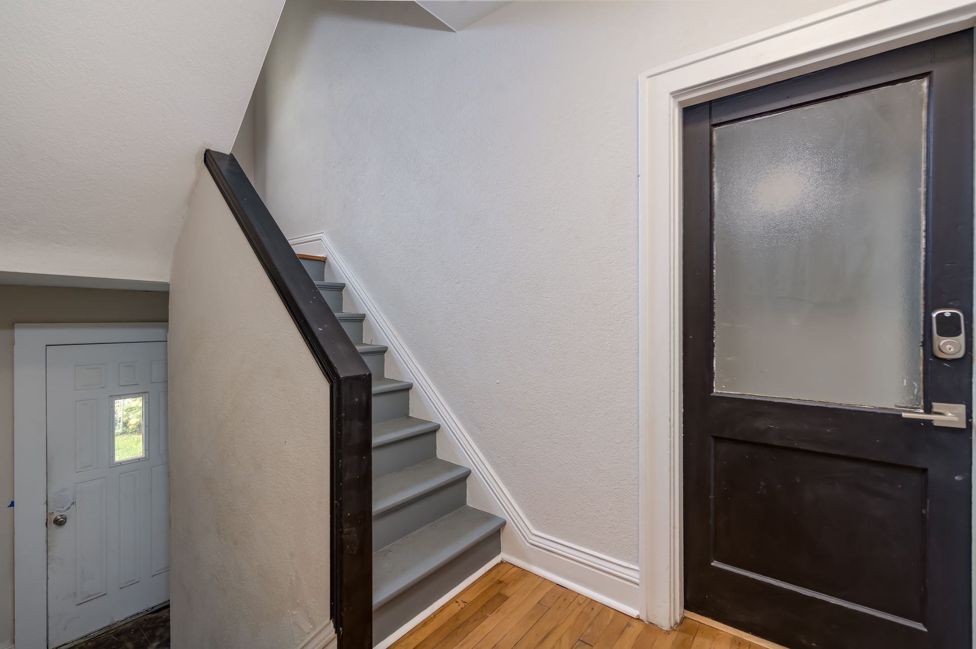 A hallway with stairs leading up to a door