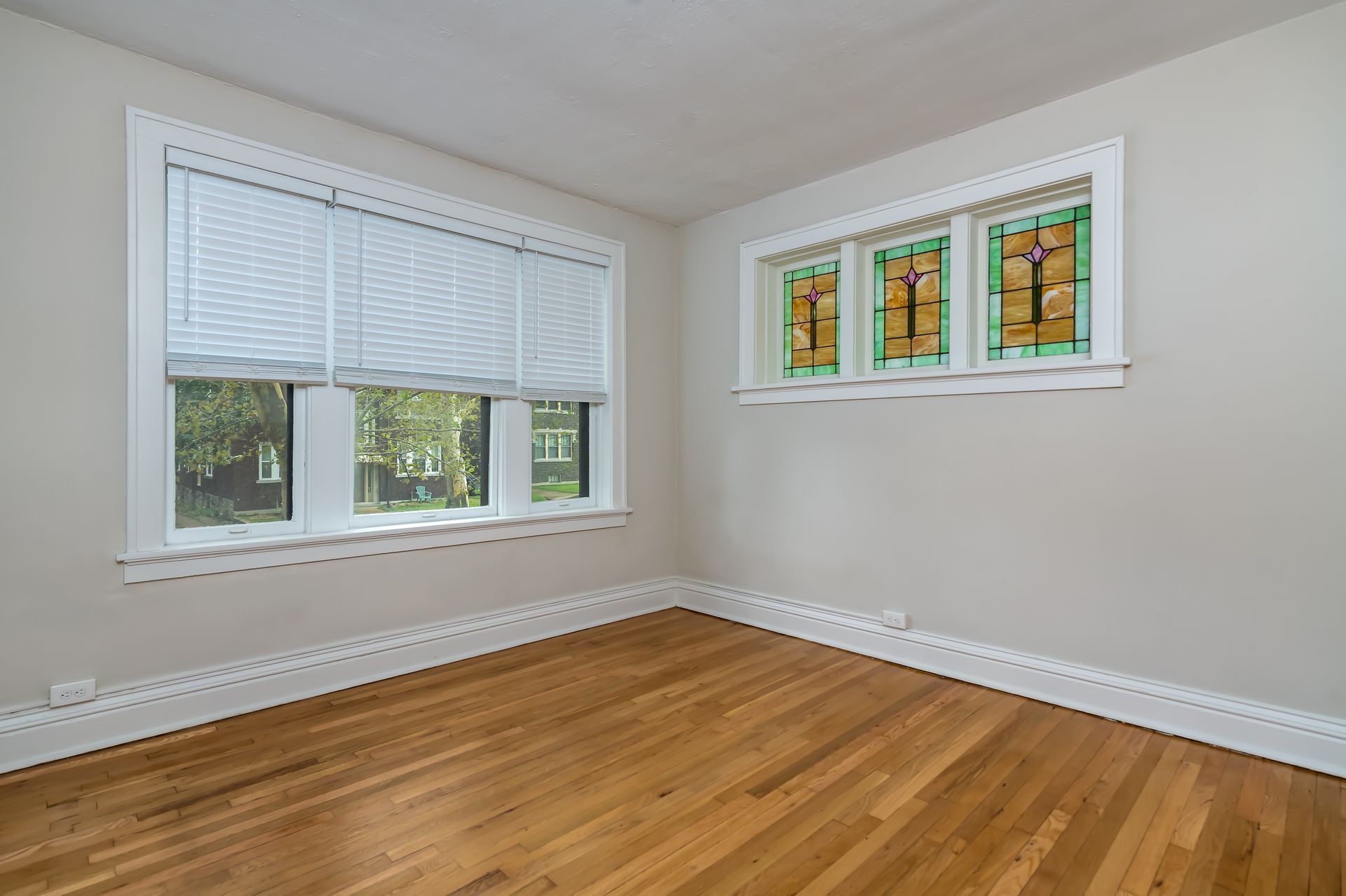 An empty room with hardwood floors and stained glass windows.