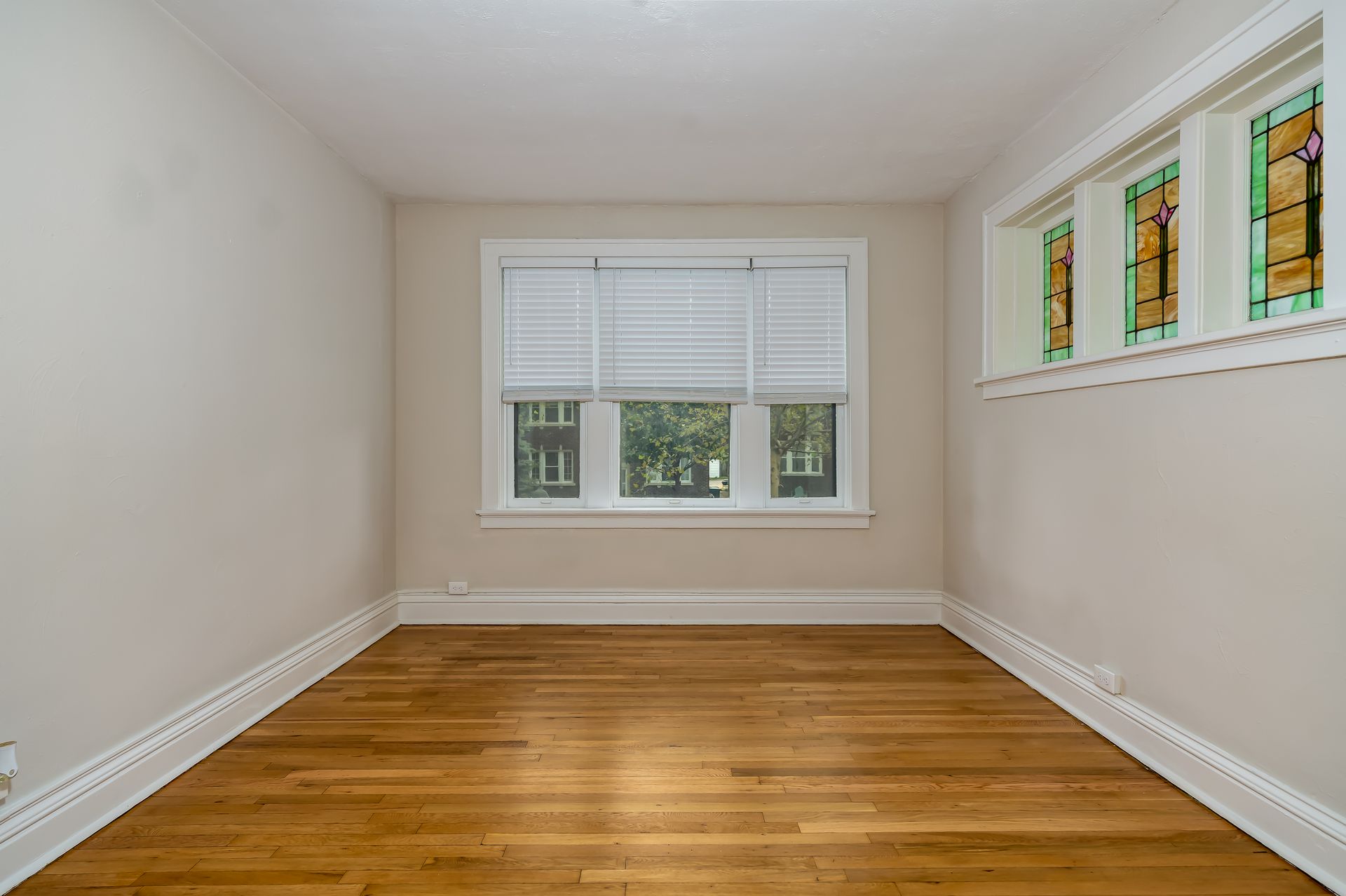 An empty room with hardwood floors and stained glass windows