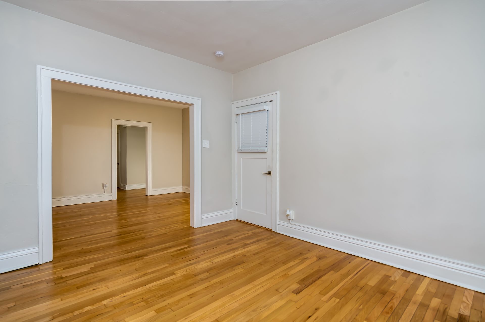 An empty room with hardwood floors and white walls.