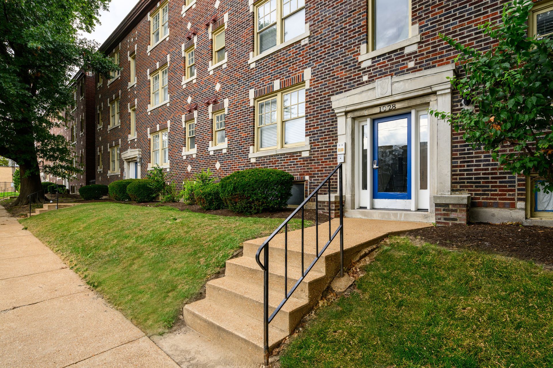 A brick building with a blue door and stairs leading up to it.