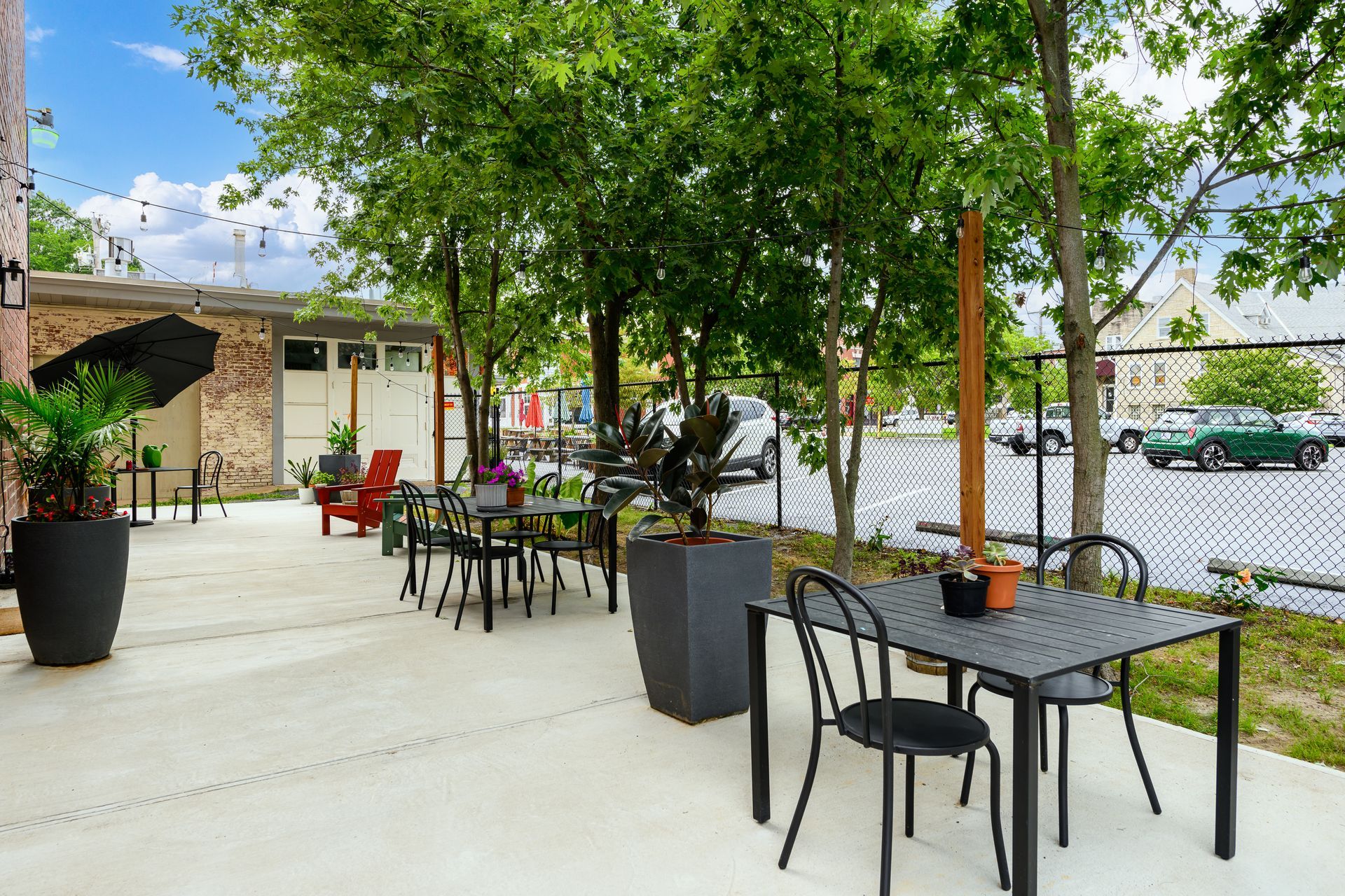 A patio with tables and chairs and trees in the background